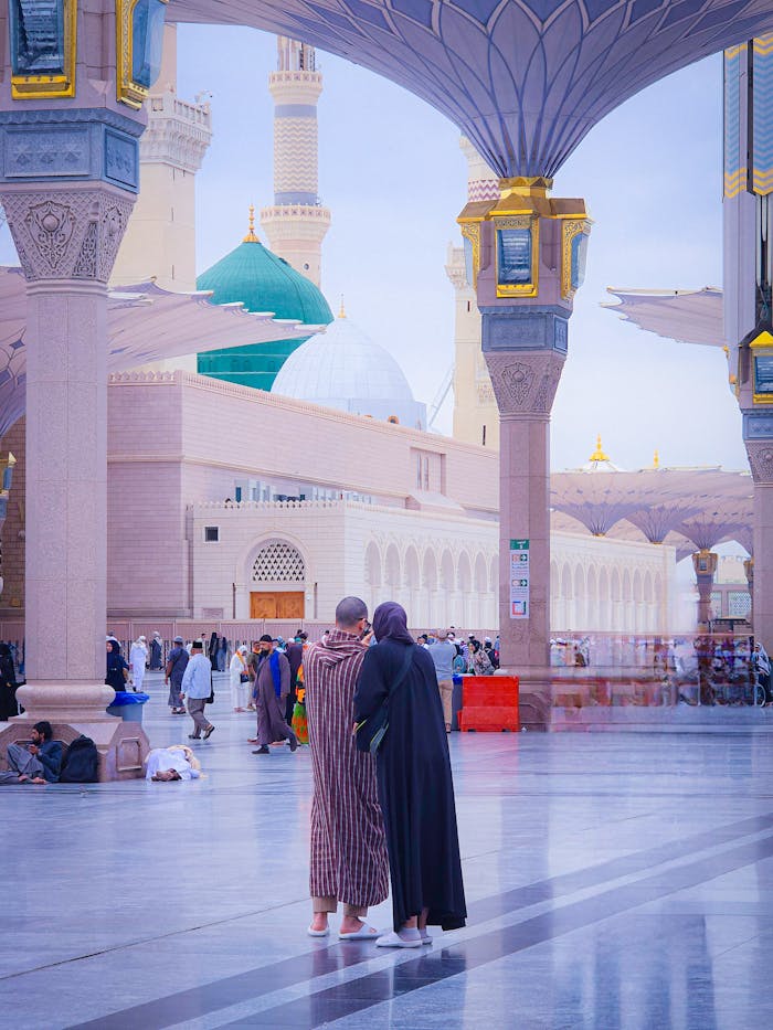 Mastering the First Impression: Your intriguing post title goes here Pilgrims stand in Al-Masjid an-Nabawi courtyard, Medina's iconic mosque.