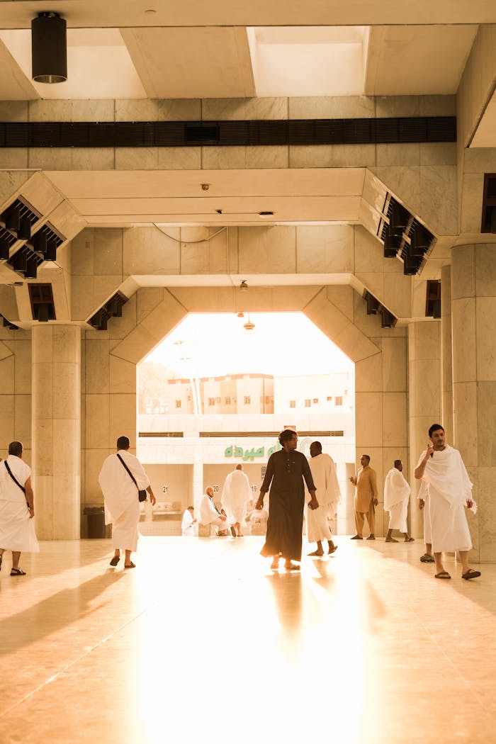 gallery-6 Pilgrims gather in traditional attire at a grand mosque entrance in Saudi Arabia.