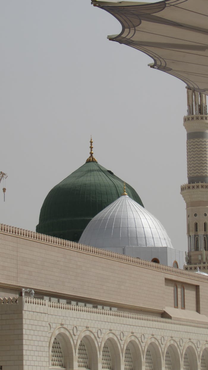 A captivating view of the iconic green and silver domes of Al-Masjid an-Nabawi, Madinah.